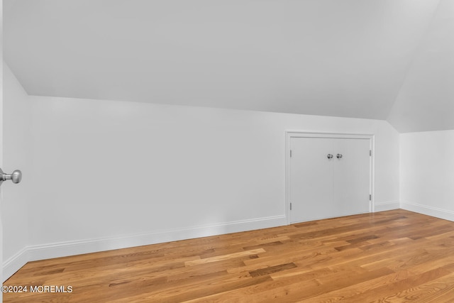additional living space featuring lofted ceiling, baseboards, and light wood finished floors