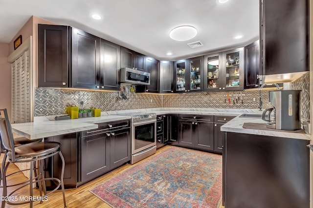 627 Huntington Dr Unit C, Lakewood, NJ 08701 - kitchen with appliances with stainless steel finishes, tasteful backsplash, light wood-style flooring, glass insert cabinets, and light stone countertops
