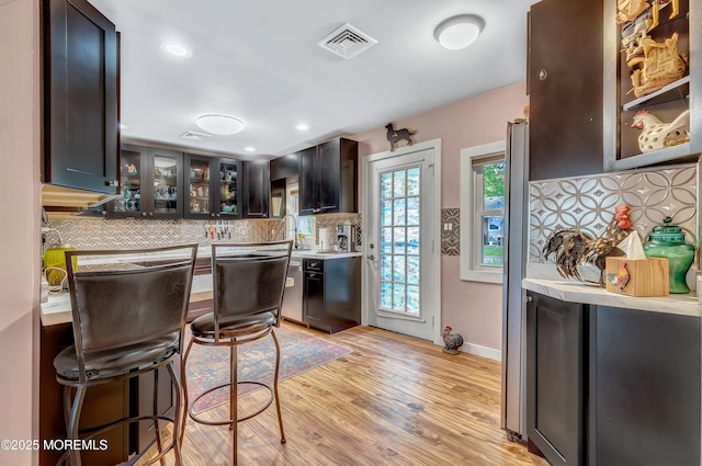 627 Huntington Dr Unit C, Lakewood, NJ 08701 - kitchen with decorative backsplash, light countertops, glass insert cabinets, light wood finished floors, and a breakfast bar