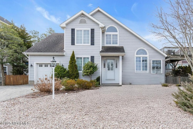 view of front facade with an attached garage, a shingled roof, driveway, and fence