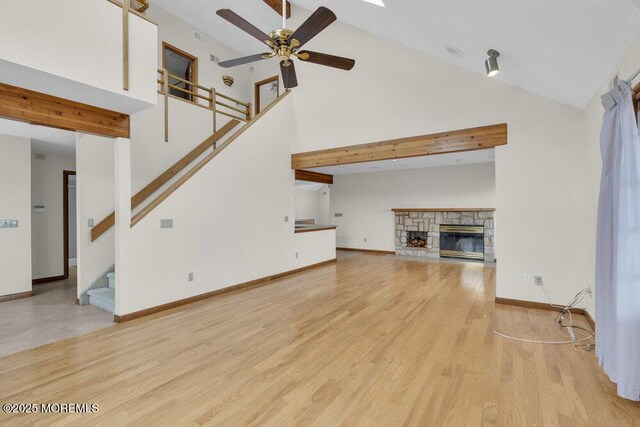 42 Circle Ct, Brick, NJ 08723 - unfurnished living room featuring light wood finished floors, a ceiling fan, stairs, a stone fireplace, and high vaulted ceiling
