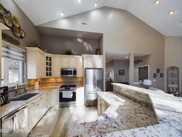 89 Pebble Beach Blvd, Jackson, NJ 08527 - kitchen featuring appliances with stainless steel finishes, a sink, cream cabinetry, high vaulted ceiling, and light stone countertops