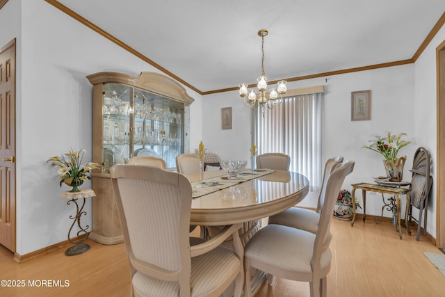 dining area with an inviting chandelier, crown molding, light wood finished floors, and baseboards