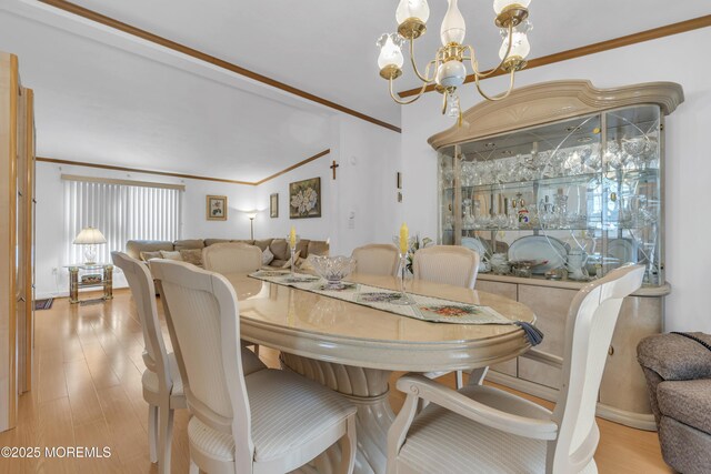 dining room with a chandelier, light wood finished floors, and ornamental molding