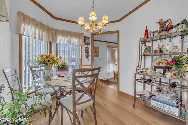 dining room with baseboards, an inviting chandelier, light wood-style floors, and crown molding