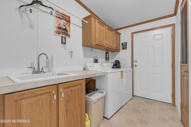 clothes washing area featuring light floors, a sink, crown molding, washer and dryer, and cabinet space