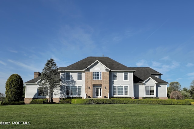 colonial inspired home featuring a chimney and a front lawn