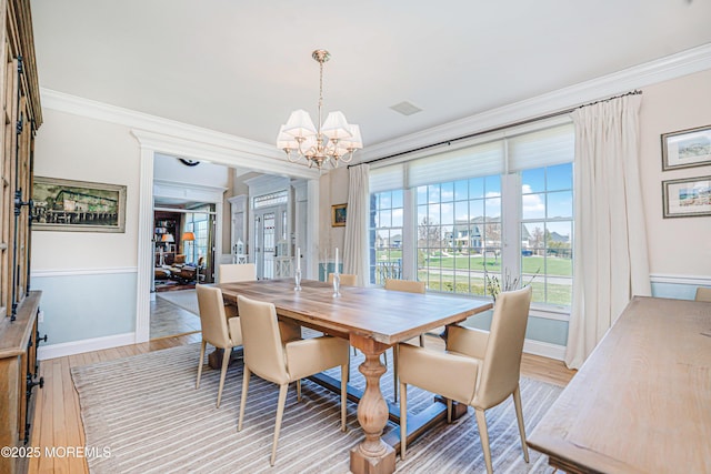 dining area featuring baseboards, an inviting chandelier, ornamental molding, and light wood-style floors