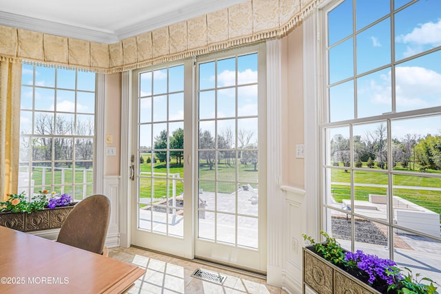 doorway to outside with crown molding, wainscoting, a decorative wall, and visible vents
