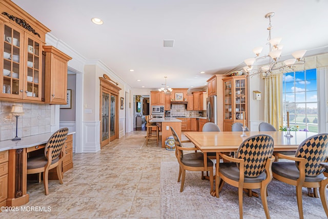 dining area with an inviting chandelier, ornamental molding, a decorative wall, recessed lighting, and a wainscoted wall