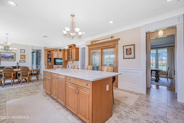 kitchen featuring a kitchen island, crown molding, a notable chandelier, and pendant lighting