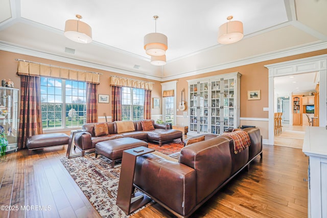 living room featuring crown molding, a tray ceiling, and hardwood / wood-style flooring