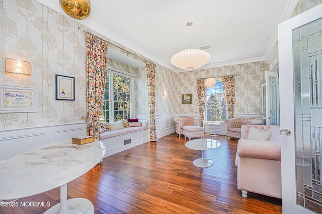 living area featuring wallpapered walls, ornamental molding, a wealth of natural light, and a wainscoted wall