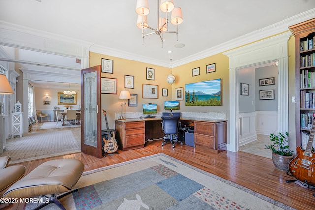 office space featuring light wood-style floors, ornamental molding, a decorative wall, and a notable chandelier
