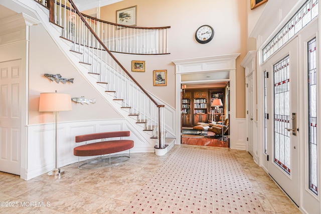 foyer with stairway, a high ceiling, and a decorative wall