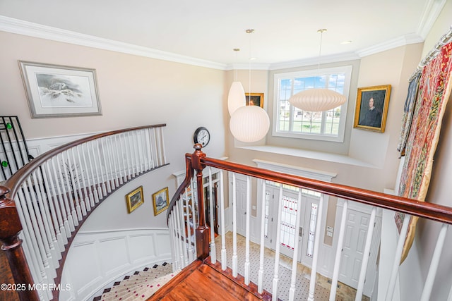 stairs featuring crown molding, a wainscoted wall, and a decorative wall