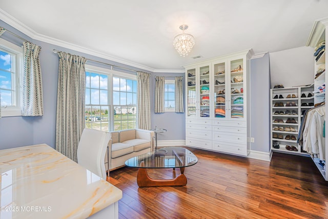 interior space with baseboards, a chandelier, ornamental molding, and wood finished floors