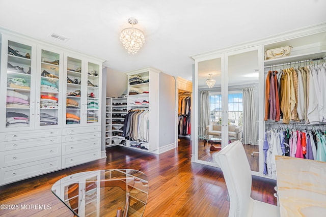 spacious closet featuring an inviting chandelier, wood finished floors, and visible vents