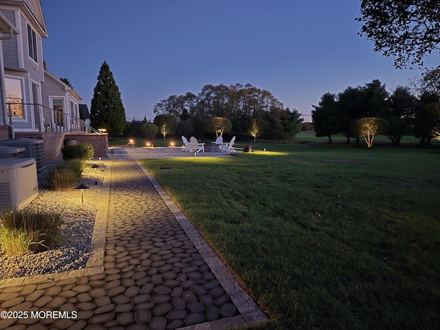 yard at dusk with a patio and central AC
