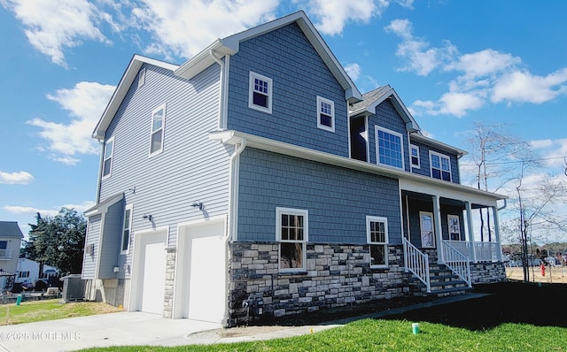 craftsman inspired home with a garage, a porch, concrete driveway, and stone siding