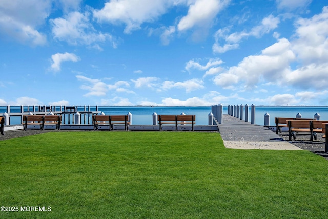 dock area with a lawn and a water view