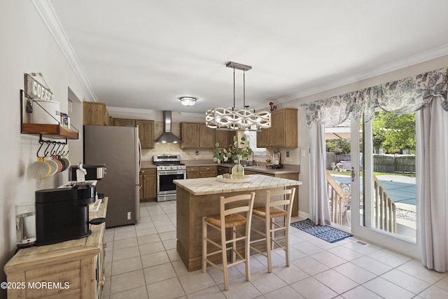 kitchen with crown molding, appliances with stainless steel finishes, light tile patterned floors, and wall chimney range hood