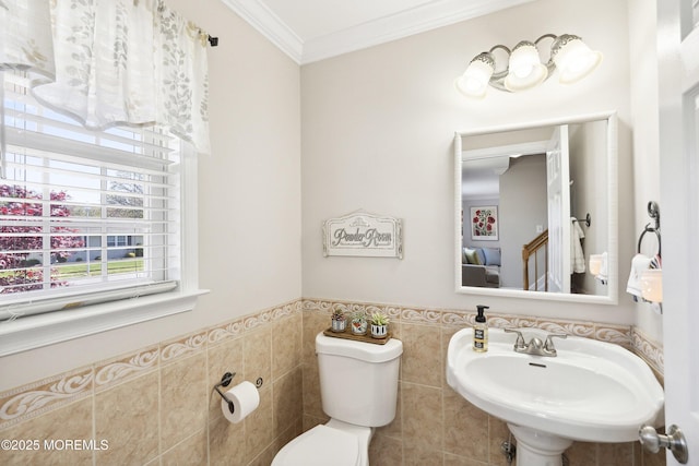 bathroom with crown molding, a wainscoted wall, toilet, and tile walls