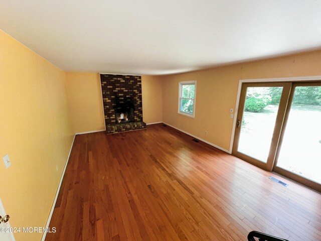 11 Green Hills Rd, East Brunswick, NJ 08816 - unfurnished living room with baseboards, a brick fireplace, wood finished floors, and visible vents