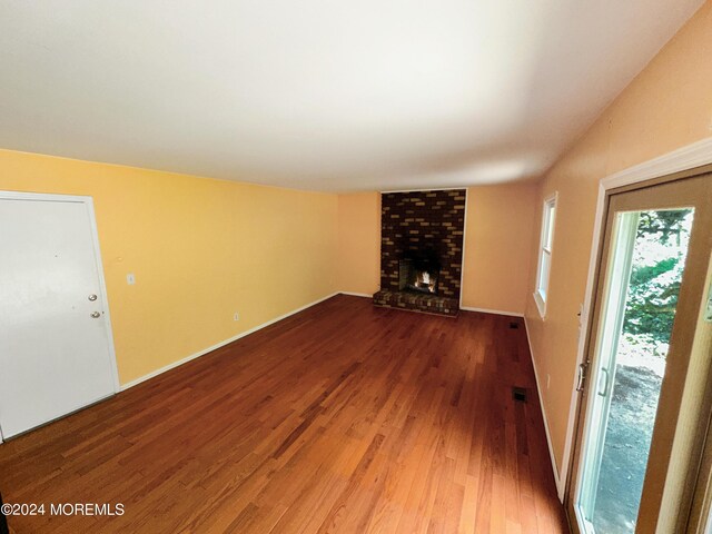 11 Green Hills Rd, East Brunswick, NJ 08816 - unfurnished living room featuring baseboards, a brick fireplace, wood finished floors, and visible vents