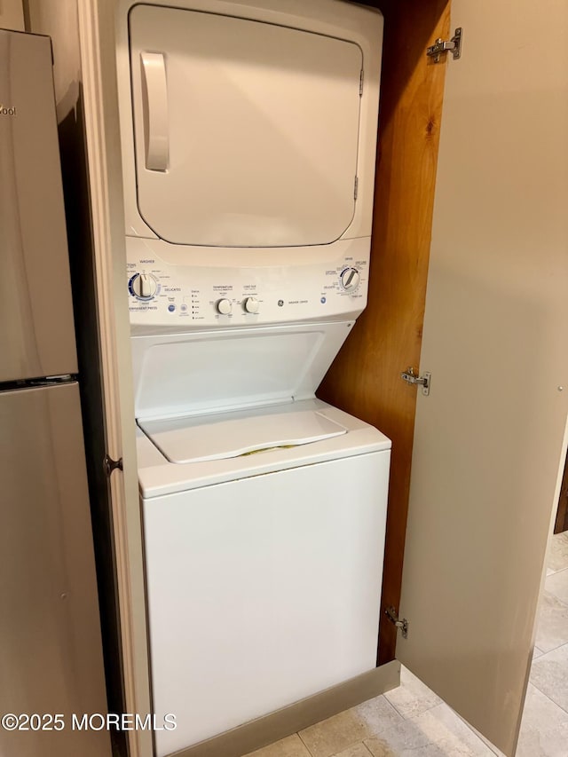 laundry area with laundry area, stacked washer / drying machine, and light tile patterned floors