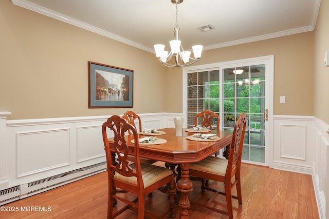 dining room featuring an inviting chandelier, crown molding, a decorative wall, and visible vents