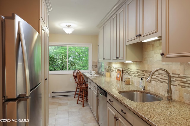 kitchen featuring baseboard heating, light stone countertops, a sink, decorative backsplash, and stainless steel appliances