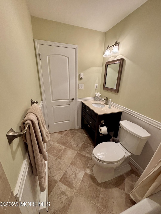 bathroom featuring vanity, toilet, and stone finish flooring