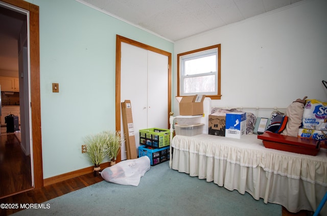 bedroom with baseboards, wood finished floors, a closet, and crown molding