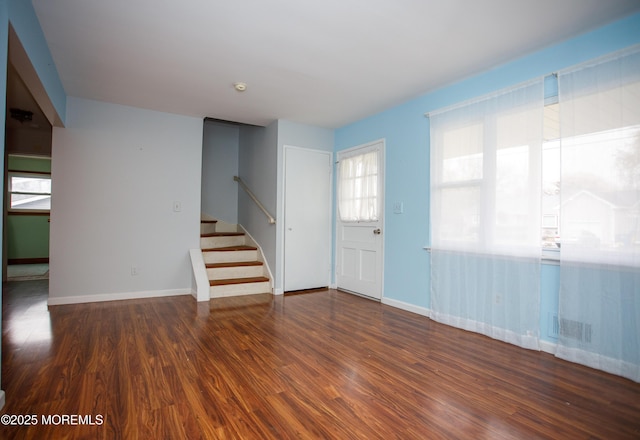 unfurnished living room with baseboards, wood finished floors, visible vents, and stairs