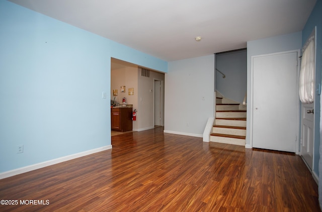 unfurnished room with dark wood finished floors, stairway, and baseboards
