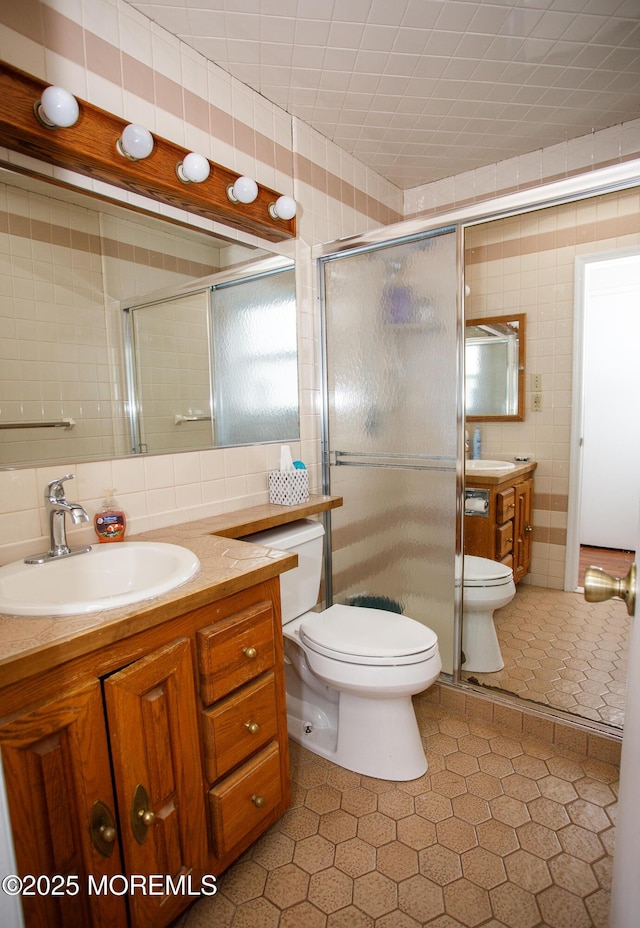 bathroom featuring tile walls, vanity, a shower stall, and toilet