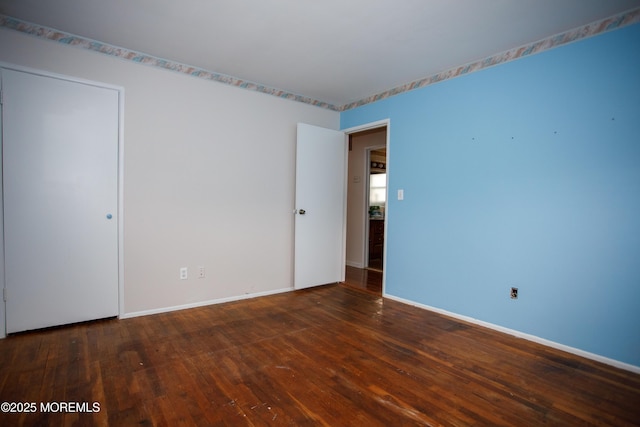 empty room featuring baseboards and wood-type flooring