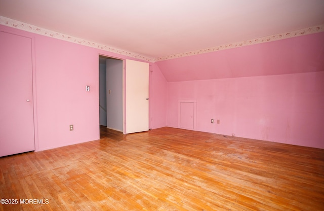additional living space with light wood finished floors and vaulted ceiling