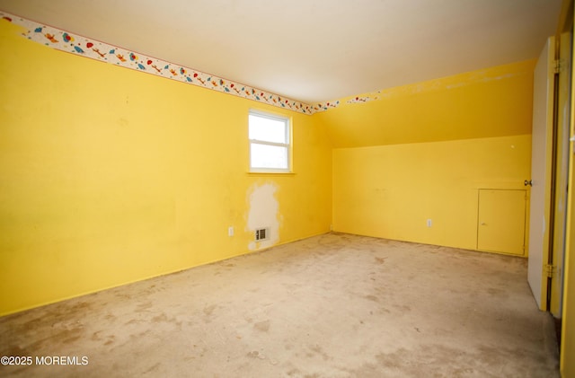 additional living space with vaulted ceiling, visible vents, and carpet flooring