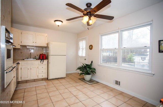 kitchen featuring stainless steel oven, visible vents, freestanding refrigerator, backsplash, and ceiling fan