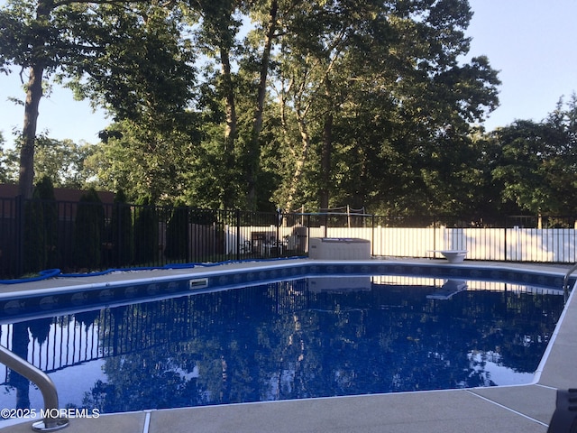 view of swimming pool featuring fence, a fenced in pool, and a diving board