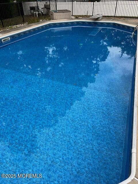 view of swimming pool featuring fence, a fenced in pool, and a diving board