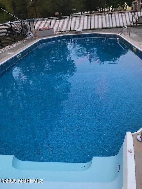 view of pool featuring a fenced in pool, fence, and a diving board