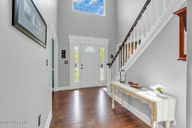 foyer entrance with baseboards, a towering ceiling, a wealth of natural light, and hardwood / wood-style floors