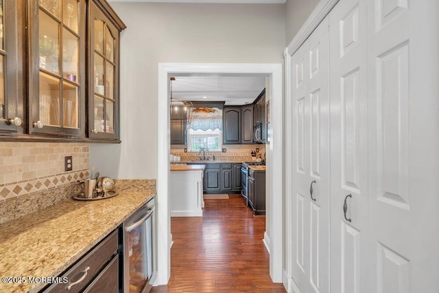 bar with wine cooler, dark wood-style floors, stainless steel microwave, a bar, and backsplash