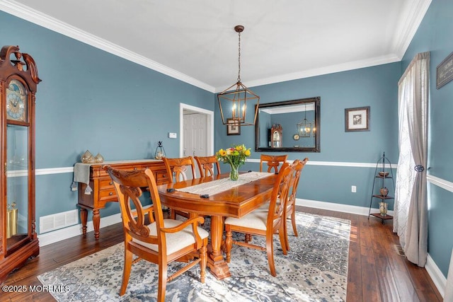 dining area featuring wood-type flooring, baseboards, crown molding, and a notable chandelier
