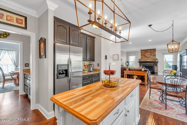 kitchen with stainless steel fridge, ornamental molding, dark wood-style floors, and butcher block counters