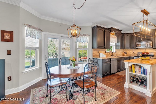 dining room featuring dark wood-type flooring, baseboards, crown molding, and a chandelier