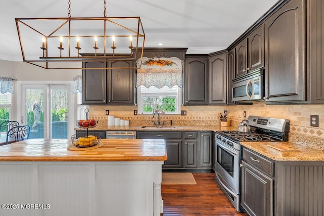 kitchen with dark wood-style flooring, appliances with stainless steel finishes, a sink, butcher block countertops, and backsplash